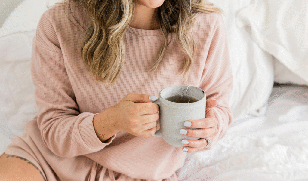 A peaceful woman sitting and holding a warm cup, symbolizing self-care, and embodying the relaxing magnesium benefits.