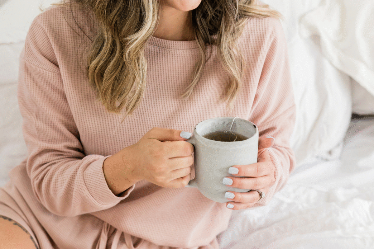 A peaceful woman sitting and holding a warm cup, symbolizing self-care, and embodying the relaxing magnesium benefits.