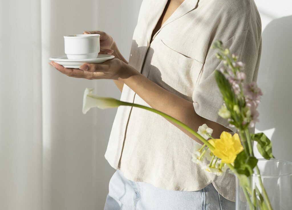 Woman holding a warm cup in morning light as she chooses wellness through simple self-care tips, mindful wellness habits, and holistic self-care