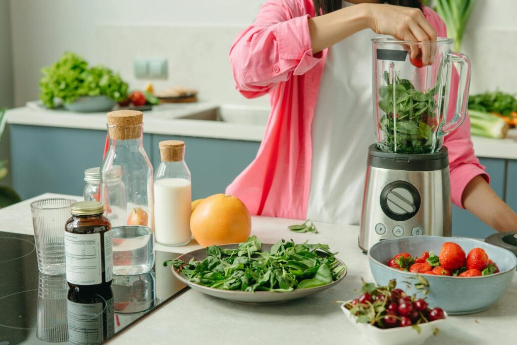 Woman in pink sleeve blending fresh fruits and veggies for a healthy magnesium smoothie. Try a delicious green smoothie with bananas, blueberries, and spinach for a healthy magnesium boost.