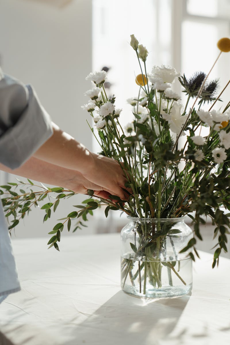 A serene floral bouquet in a glass vase with natural sunlight symbolizing calm, gentle wellness and practical self-care.
