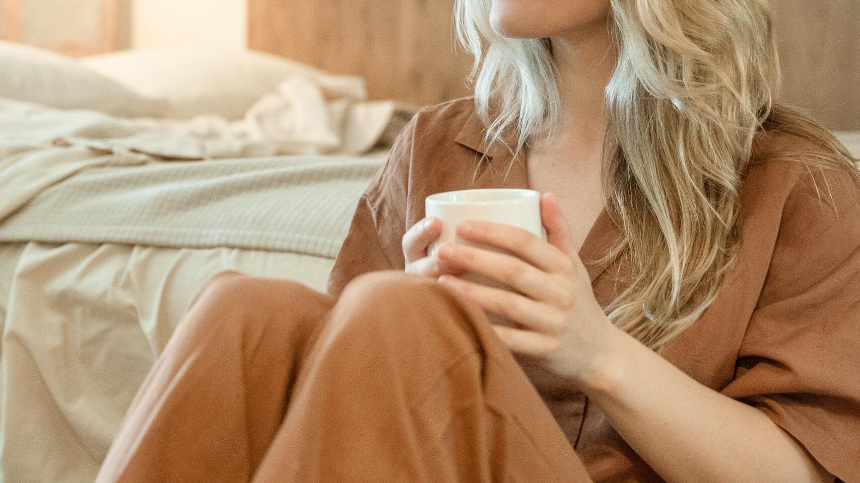 Woman practicing self-care with simple self-care habits, holding a warm cup in her bedroom during her emotional healing journey.