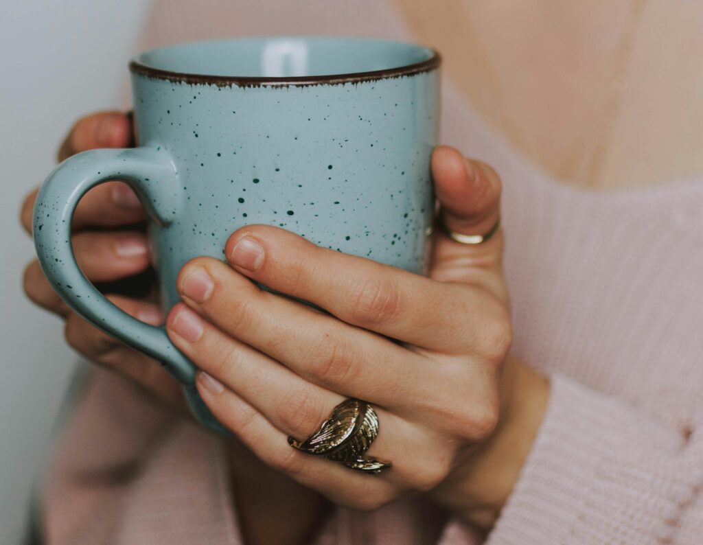 Woman practicing self-care with simple self-care habits, holding a warm cup in her bedroom during her emotional healing journey.